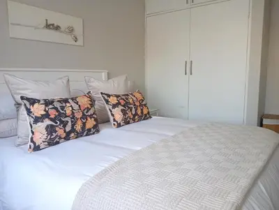 a bedroom with a large white bed with pillows at Willows Garden Cottage in Pretoria