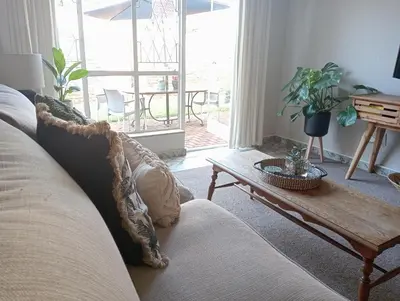 a living room with a couch and a wooden table at Willows Garden Cottage in Pretoria