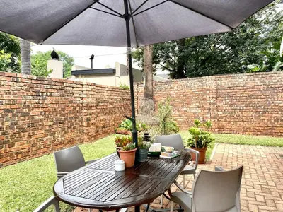 a wooden table and chairs with an umbrella at Willows Garden Cottage in Pretoria
