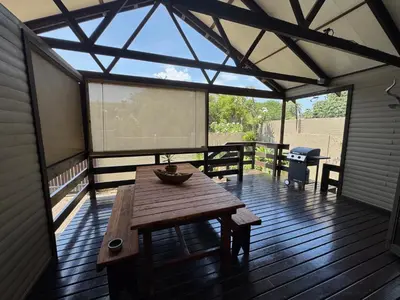 a screened in porch with a wooden table on a deck at Timmerstuga in Malelane