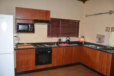 a kitchen with wooden cabinets and a white refrigerator at Thabaledi Game Lodge in Brits