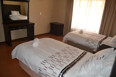 a hotel room with two beds and a mirror at Thabaledi Game Lodge in Brits