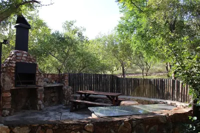 a stone fireplace with a picnic table and a wooden fence at Thabaledi Game Lodge in Brits