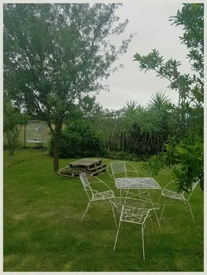 a table and chairs in a yard with a tree at Die Woestynroos Gastehuis in Isidule