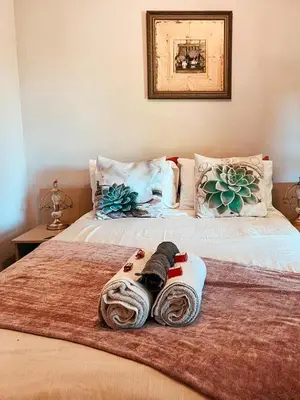 a bed with two blankets and towels on it at Die Woestynroos Gastehuis in Isidule