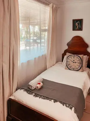 a bedroom with a bed with a clock and a window at Die Woestynroos Gastehuis in Isidule