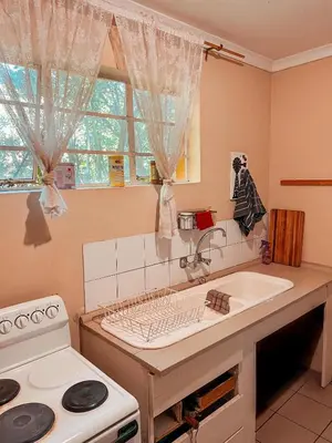 a kitchen with a sink and a stove and a window at Die Woestynroos Gastehuis in Isidule