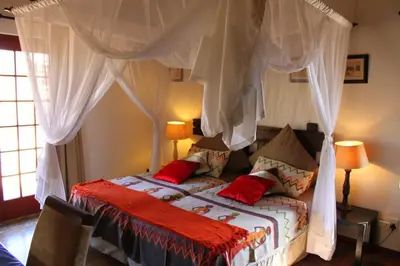 a bedroom with a canopy bed with red pillows at Bushvilla Umoja Kruger in Phalaborwa