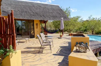 a villa with a thatched roof and a swimming pool at Bushvilla Umoja Kruger in Phalaborwa