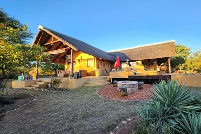a house with a thatched roof and a yard at Bushvilla Umoja Kruger in Phalaborwa