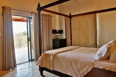 a bedroom with a canopy bed and a sliding glass door at Kierieklapper in Hectorspruit