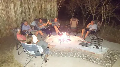 a group of people sitting around a fire pit at Kierieklapper in Hectorspruit