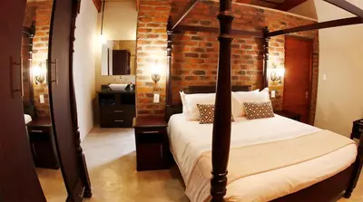 a bedroom with a bed and a brick wall at Kierieklapper in Hectorspruit