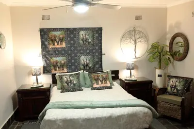 a bedroom with a bed and two tables and two lamps at Thorn Tree Bush Camp in Klipdrift