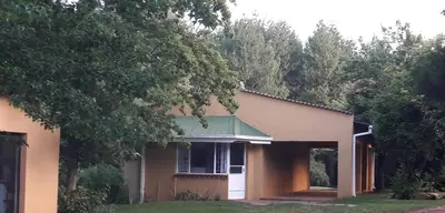 a house with a green roof and a tree at Sanfern Downs Cottage in Haenertsburg