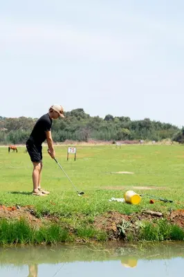 a man is playing golf near the water at Riverman Cabin Country Lodge - Tonteldoos in Tonteldoos