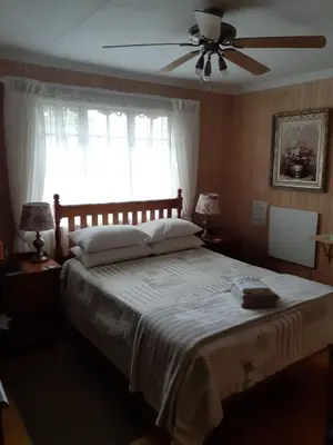 a bedroom with a large bed with a ceiling fan at Kattekwaad Accommodation in Kaapsehoop