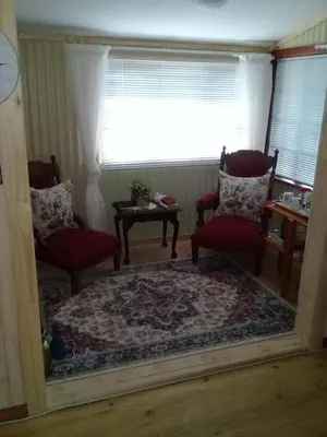 a mirror in a living room with two chairs and a window at Kattekwaad Accommodation in Kaapsehoop