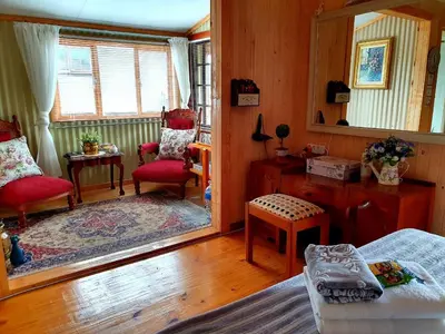a bedroom with a mirror and a bed and chairs at Kattekwaad Accommodation in Kaapsehoop