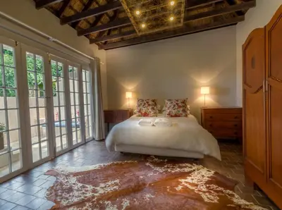 a bedroom with a bed in a room with windows at Pierneef's Kraal in Pretoria