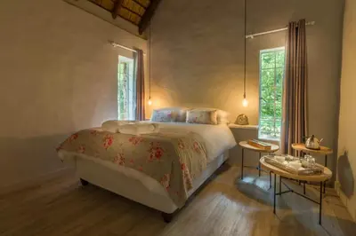 a bedroom with a large bed and two tables at Pierneef's Kraal in Pretoria