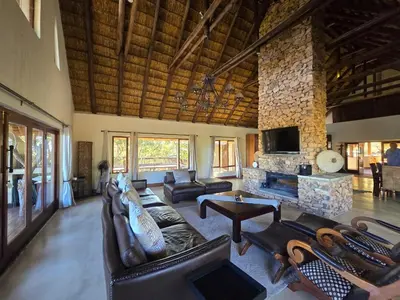 a living room with leather furniture and a stone fireplace at Mingwe Private Game Lodge in Mabula