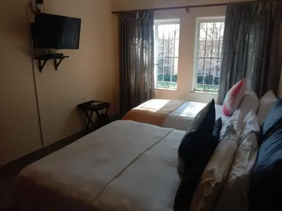 a hotel room with two beds and a television at LightStone Guesthouse in Centurion