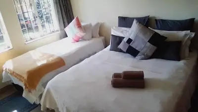 two beds sitting next to each other in a room at LightStone Guesthouse in Centurion