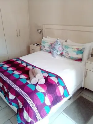 a white bed with a colorful blanket and two towels at LightStone Guesthouse in Centurion