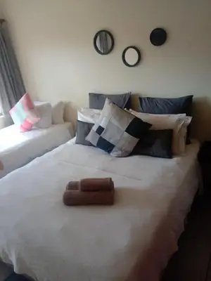 a large white bed in a room with a couch at LightStone Guesthouse in Centurion
