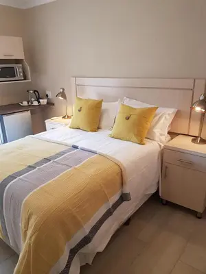 a bedroom with a large bed with yellow pillows at LightStone Guesthouse in Centurion