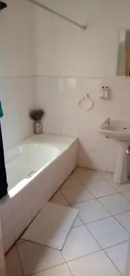 a white bathroom with a tub and a sink at LightStone Guesthouse in Centurion