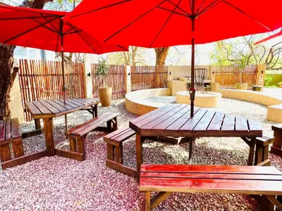 a picnic table and benches with red umbrellas at Echo Mountain Inn in Thabazimbi