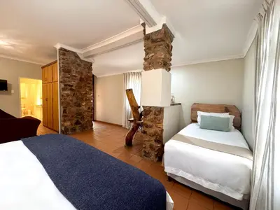 a bedroom with two beds and a stone wall at Centurion Guest House and Lodge in Centurion