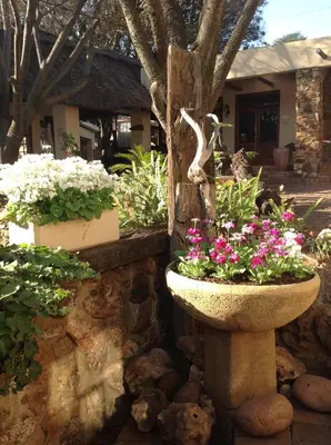 a stone bowl filled with flowers in front of a house at Centurion Guest House and Lodge in Centurion