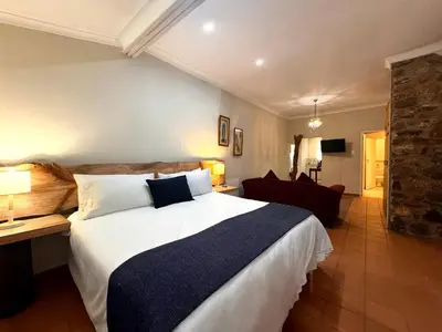 a hotel room with a large bed and a chair at Centurion Guest House and Lodge in Centurion