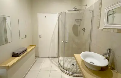 a bathroom with a glass shower and a sink at Centurion Guest House and Lodge in Centurion