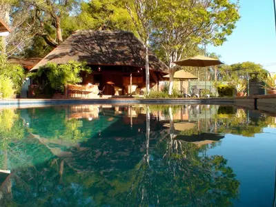 a house with a pool of water with a thatch roof at Polokwane Place in Polokwane