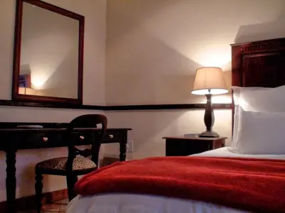 a bedroom with a bed and a mirror and a chair at Polokwane Place in Polokwane
