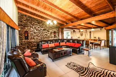 a living room with leather furniture and a stone wall at The Rest Guest House in Nelspruit
