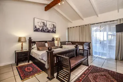 a bedroom with a bed and a chair and a window at The Rest Guest House in Nelspruit