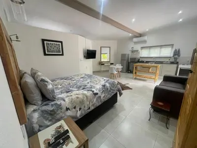a bedroom with a bed and a living room at The Rest Guest House in Nelspruit