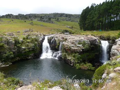 a waterfall in a field next to a body of water at Joy River Backpackers in Moremela