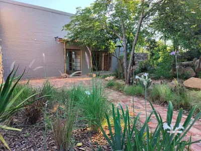 a garden with a purple building and plants at Eloff Guest House and Gallery in White River
