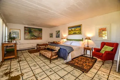 a bedroom with a bed and a couch and a chair at Eloff Guest House and Gallery in White River