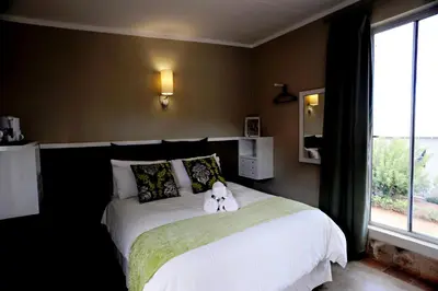 a teddy bear sitting on a bed in a bedroom at Villa Paradiso in Hartbeespoort