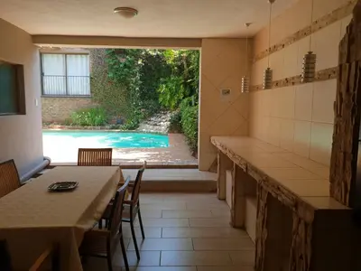 a kitchen with a table and a view of a pool at Fa'Trez Guest House & Spa in Pretoria