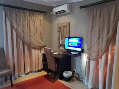 a room with a desk with a computer and a chair at Fa'Trez Guest House & Spa in Pretoria