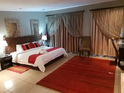 a bedroom with a large bed and a red rug at Fa'Trez Guest House & Spa in Pretoria