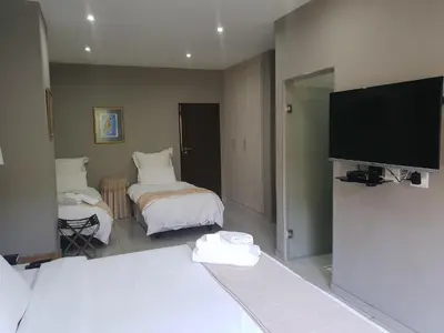 a room with two beds and a flat screen tv at Fa'Trez Guest House & Spa in Pretoria